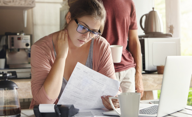 A hand with coins on a scale, illustrating how a deductible works for condo insurance.